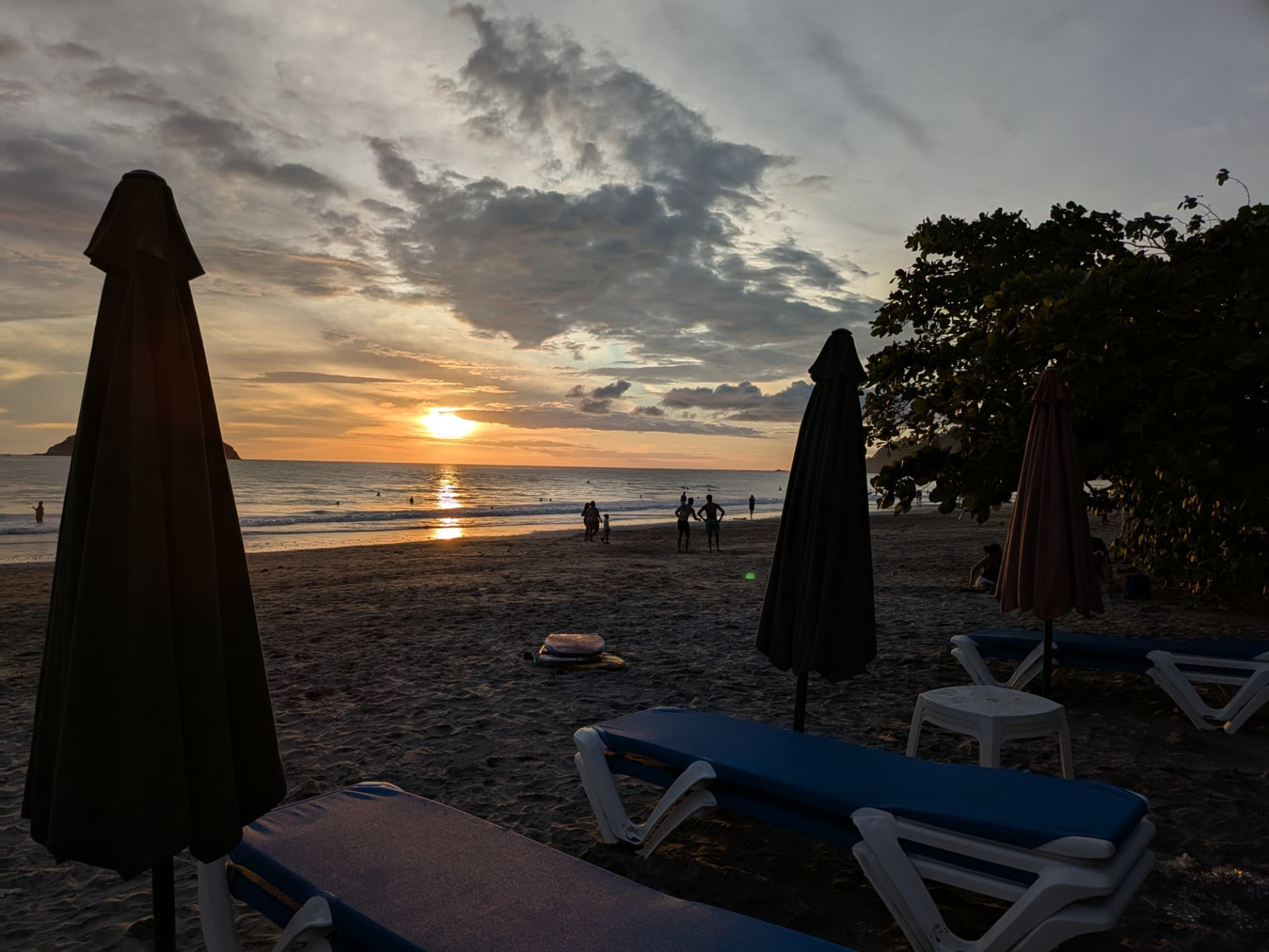 Golden sunset over Playa Espadilla with beach loungers and silhouettes on the shore